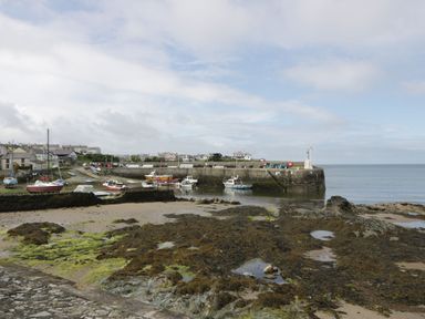 A small harbor with boats docked and rocky shoreline at Ty Bara in Cemaes Bay