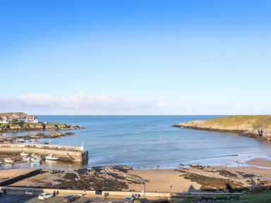 A coastal scene with a harbor and boats on the water at Ty Bara in Cemaes Bay