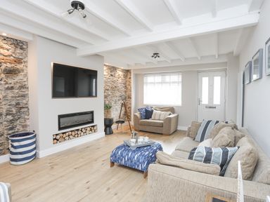 A living room with sofas a television and fireplace at Ty Bara in Cemaes Bay