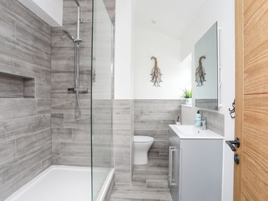 A bathroom with a walkin shower toilet sink and mirror at Ty Bara in Cemaes Bay