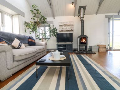 A living room with a sofa coffee table television and a wood burning stove at An Skyber in Perranuthnoe