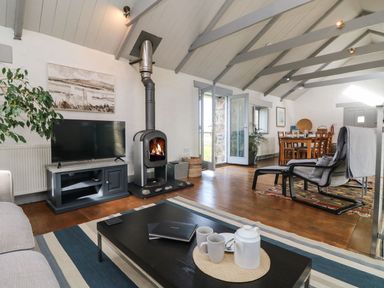 A living room with a fireplace television coffee table and dining table at An Skyber in Perranuthnoe