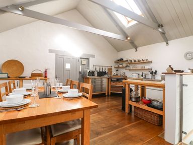 A kitchen and dining area with wooden furniture and kitchen appliances at An Skyber in Perranuthnoe