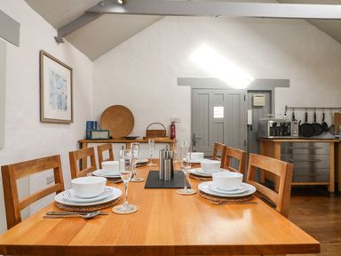 A dining room with a wooden table set for six people in a kitchen at An Skyber in Perranuthnoe