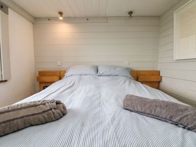 A bedroom with a bed made with striped bedding and two rolled towels on it at An Skyber in Perranuthnoe