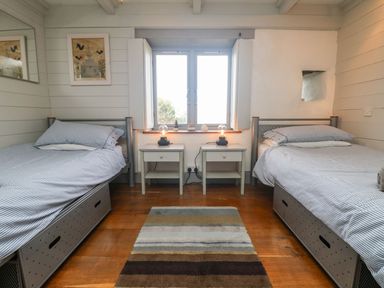 A bedroom with two single beds two bedside tables and a window at An Skyber in Perranuthnoe