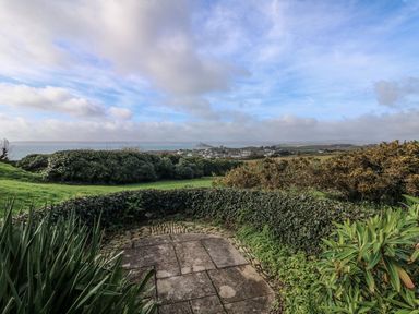 A garden with hedges and plants overlooking a coastal village and the sea at An Skyber in Perranuthnoe