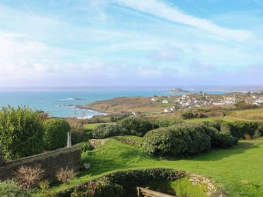 A coastal landscape view with green bushes and grass overlooking a village and ocean at An Skyber in Perranuthnoe