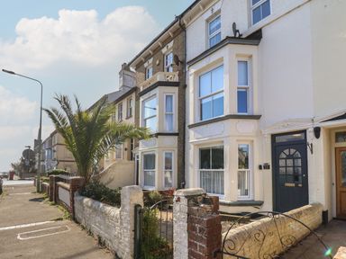 A row of terraced houses with bay windows and small front gardens on a street with a palm tree at First Light in Pakefield near Lowestoft