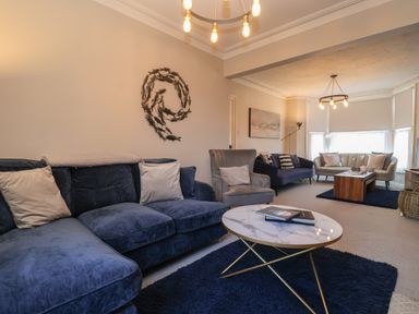 A living room with blue and gray sofas and a marble coffee table at First Light in Pakefield near Lowestoft