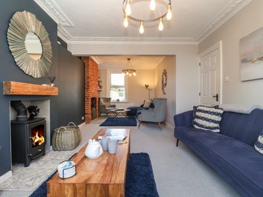 A living room with a wood stove fireplace coffee table sofas armchairs and decorative items at First Light in Pakefield near Lowestoft