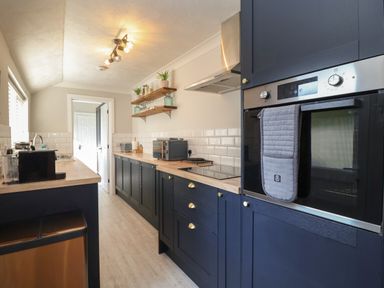 A kitchen with dark cabinets wooden countertops and appliances at First Light in Pakefield near Lowestoft