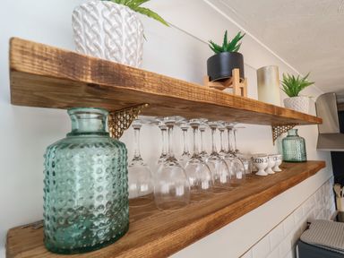 Wooden shelves with glassware green vases small plants and white ceramic cups in a kitchen at First Light in Pakefield near Lowestoft