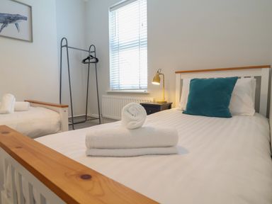A bedroom with two single beds white towels and a blue cushion at First Light in Pakefield near Lowestoft