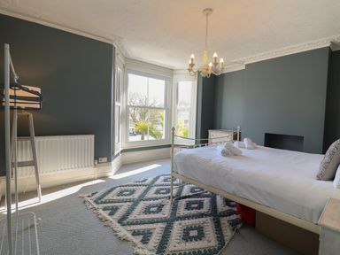 A bedroom with a bed and towels on it alongside a dresser and window at First Light in Pakefield near Lowestoft