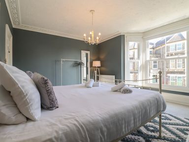 A bedroom with a bed and pillows next to a window with a view of houses at First Light in Pakefield near Lowestoft