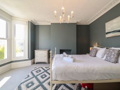 A bedroom with a bed white linens and rolled towels a chandelier and a chest of drawers at First Light in Pakefield near Lowestoft
