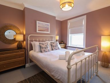 A bedroom with a bed pillows lamps and a window at First Light in Pakefield near Lowestoft