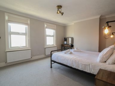 A bedroom with a bed pillows and towels near a dressing table at First Light in Pakefield near Lowestoft