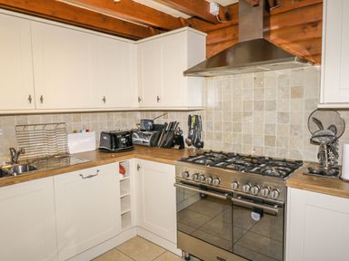 A kitchen with white cabinets a stainless steel stove toaster and knife set at Thistle Dubh Doo in Sandyhills