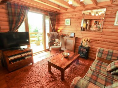 A living room with a sofa and television at Thistle Dubh ("Doo") Sandyhills