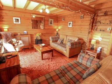 A living room with a sofa and armchair at Thistle Dubh ("Doo") in Sandyhills