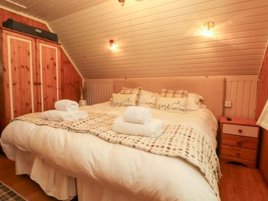 A bedroom with a bed and wardrobe at Thistle Dubh ('Doo') in Sandyhills