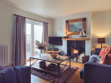 A living room with a wooden coffee table flowers and fruit bowl on the table a fireplace and sofa at Craster Reach in Craster