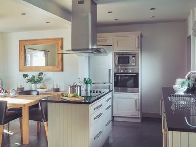 A kitchen with a dining table chairs built in oven microwave and cooktop at Craster Reach in Craster