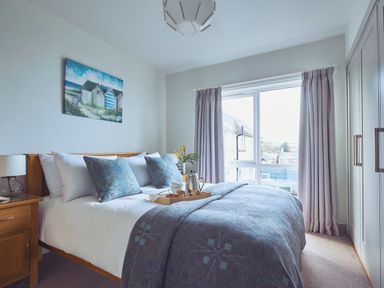 A bedroom with a bed a side table a window with curtains and a wardrobe at Craster Reach in Craster