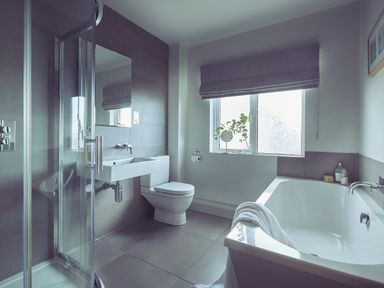 A bathroom with a glass shower cubicle bathtub toilet and window at Craster Reach in Craster