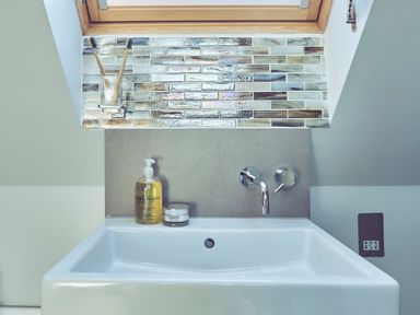 A bathroom sink with a soap dispenser toothbrushes and a window at Craster Reach in Craster