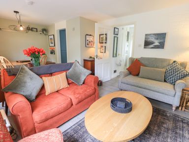 A living room with two sofas a wooden coffee table and a dining table with flowers at Little Hallgarth in Keswick