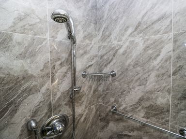 A shower area with a handheld showerhead mounted on a tiled wall with a soap dish and a grab bar at Little Hallgarth in Keswick