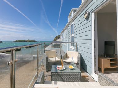 A balcony with wicker furniture and a glass table overlooking the sea at Rebecca in Mullion Cove near Mullion
