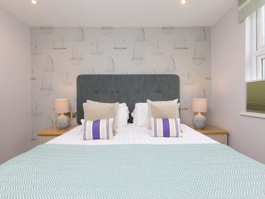 A bedroom with a double bed two bedside tables with lamps and a window with a blind at Rebecca in Mullion Cove near Mullion