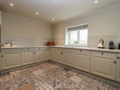 A kitchen with patterned tile floor a window above the sink and cabinets along two walls at Millpond Bothy in Woolhope