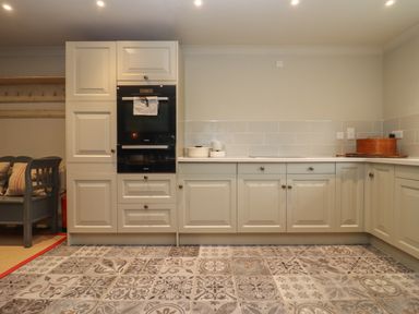 A kitchen with built-in oven cabinets and patterned tile flooring at Millpond Bothy in Woolhope