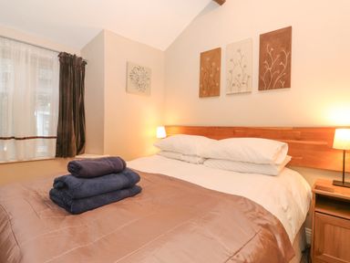A bedroom with a double bed and folded towels on top at Myrtle Cottage in Windermere