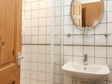 A bathroom with a sink faucet mirror glass shelf and shower at Myrtle Cottage in Windermere