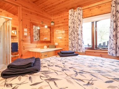 A bedroom with a bed and folded towels next to a window with curtains at Hayeswater Lodge Burnside Park near Keswick