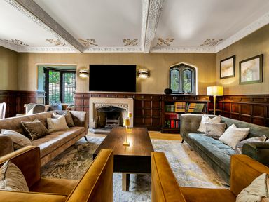 A living room with sofas armchairs a wooden coffee table a fireplace and a television at Tudor Grange in Bournemouth