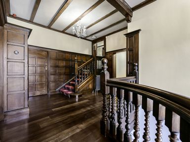 A wooden staircase with red carpet and wood paneled walls in a hallway at Tudor Grange in Bournemouth