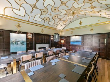 A conference room with wooden tables and chairs and a decorative ceiling at Tudor Grange in Bournemouth