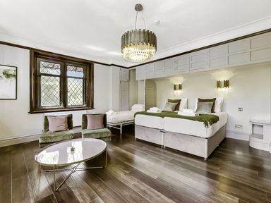 A bedroom with two single beds a pull-out bed two green chairs and a coffee table at Tudor Grange in Bournemouth