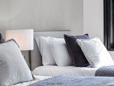 A bedroom with two beds a lamp on a bedside table and pillows at Tudor Grange in Bournemouth