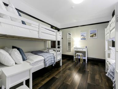 A bedroom with two white bunk beds a white side table and a white desk with a stool at Tudor Grange in Bournemouth