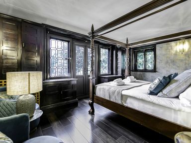 A bedroom with a four-poster bed pillows and rolled towels near a window and lamp at Tudor Grange in Bournemouth