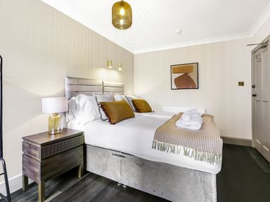 A bedroom with a double bed bedside table lamp and artwork on the wall at Tudor Grange in Bournemouth