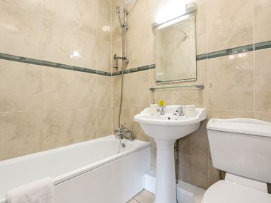 A bathroom with a bathtub shower sink mirror and toilet at Tudor Grange in Bournemouth